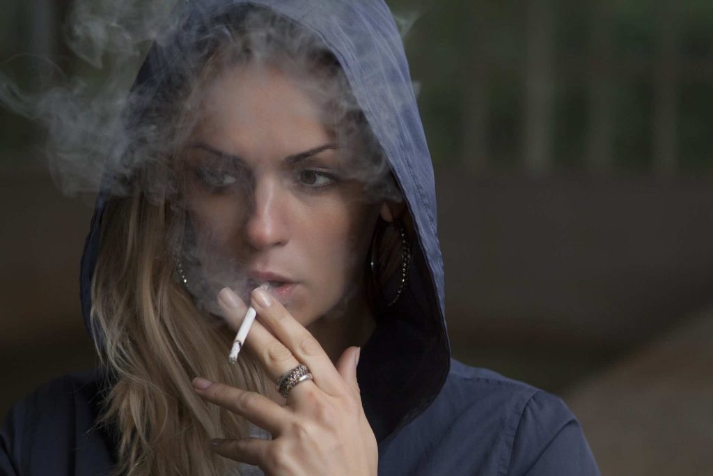Woman smoking a cigarette with her hood up